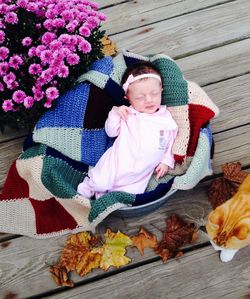 High angle view of baby sleeping in crib by cat