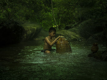 Full length of boy sitting in forest
