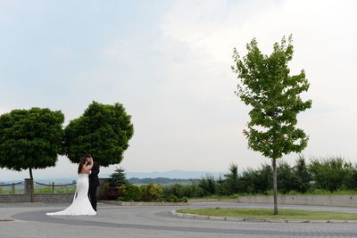 Woman standing by road against sky