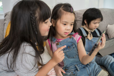 Children using technologies on sofa in living room at home