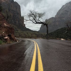Wet road by rocky mountain during rainy season