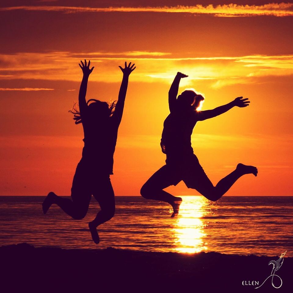 TWO PEOPLE PLAYING ON BEACH AT SUNSET