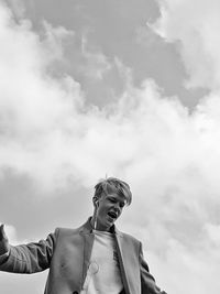 Low angle view of man with headphones against cloudy sky