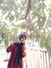 Young woman standing against tree