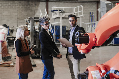 Engineers discussing over robotic arm in industry