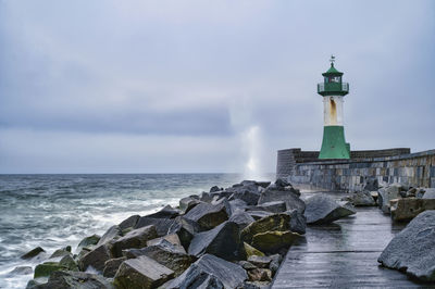 Lighthouse by sea against sky