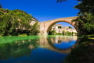 Arch bridge over river against blue sky