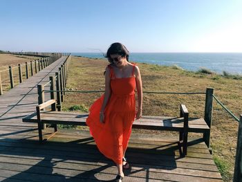 Full length of woman walking on wood against sea and sky