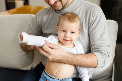 Midsection of father with baby at home