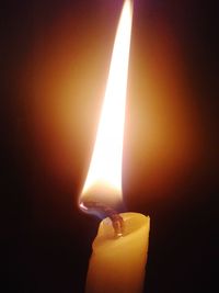 Close-up of lit candle in darkroom