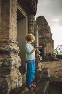 Full length of young woman standing at doorway of angkor wat