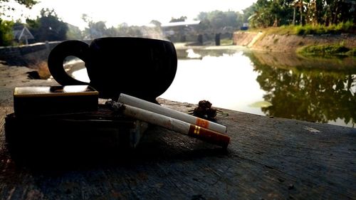 Close-up of cigarette on table by lake