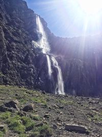 Scenic view of waterfall against bright sun