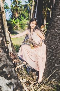 Portrait of young woman sitting on tree trunk