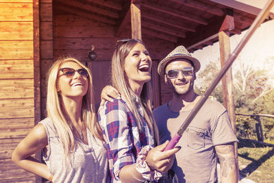 Portrait of smiling friends standing against wall