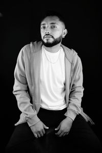 Portrait of young man against black background