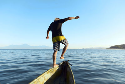 Man jumping from boat into sea