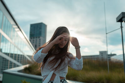 Young woman standing against sky