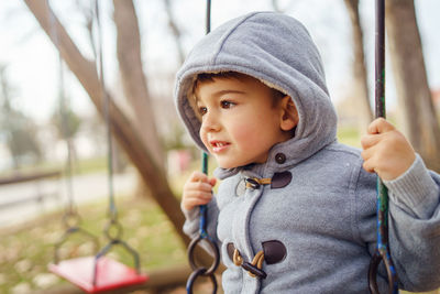 Close-up of cute boy in swing at park