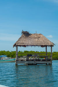 Stilt house by sea against blue sky