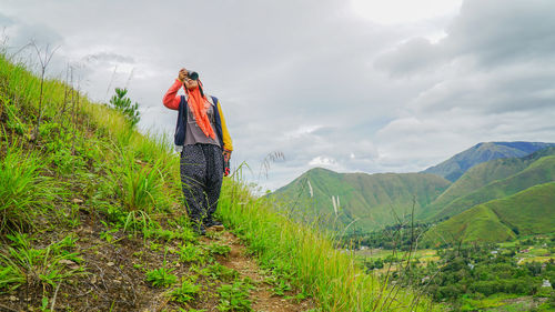 Woman with umbrella on landscape against sky