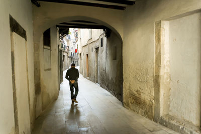 Rear view of woman walking in alley amidst buildings