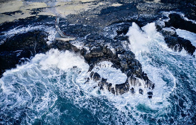 Waves rolling over cliff in ocean
