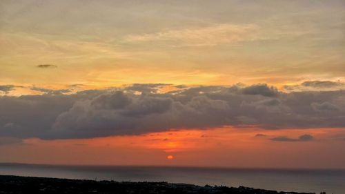 Scenic view of sea against dramatic sky during sunset