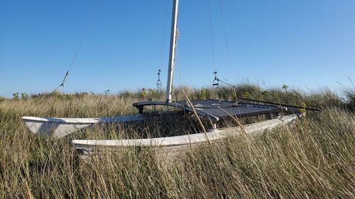 Sailboats moored on field against clear blue sky