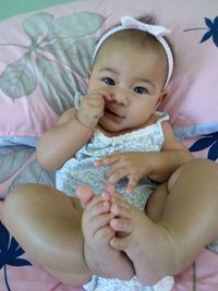 Portrait of cute baby girl lying on bed at home