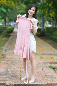 Full length of happy woman standing against pink umbrella