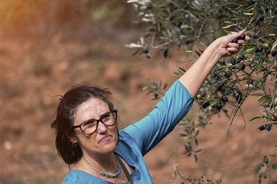 Portrait of young woman standing against trees