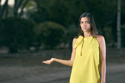 Portrait of young woman standing against trees