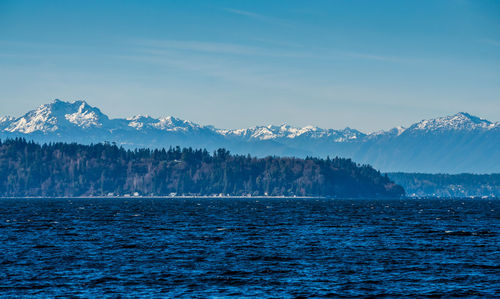 Scenic view of sea and snowcapped mountains against sky