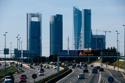 Traffic on road by buildings against sky