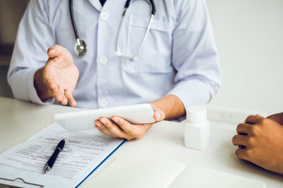 Midsection of doctor explaining patient on table