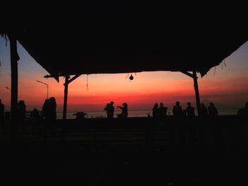 Silhouette people on landscape against sky during sunset