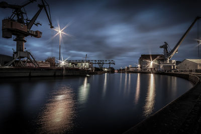Illuminated pier at harbor against sky at night