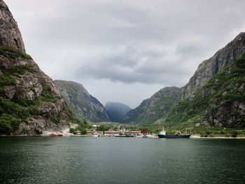 Scenic view of fjord amidst cliffs against cloudy sky