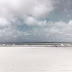 Scenic view of beach against cloudy sky