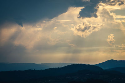 Scenic view of silhouette mountains against dramatic sky