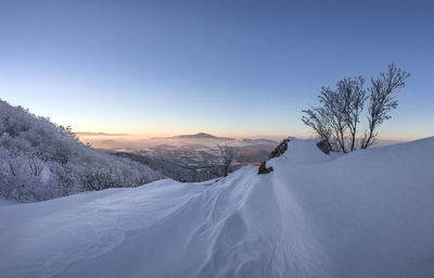 Scenic view of snow covered landscape against clear sky