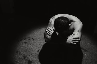 Rear view of person with arms raised in darkroom