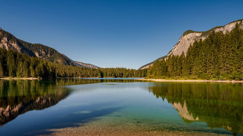 Scenic view of lake and mountains against clear blue sky