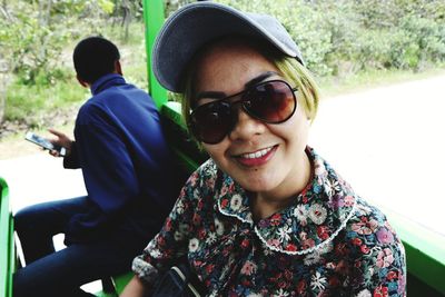 Portrait of smiling woman wearing sunglasses sitting in land vehicle