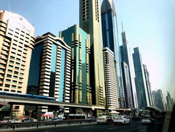 View of city street and modern buildings against sky