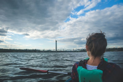 Woman exploring by the river. young woman on kayak in the sea with blue sky