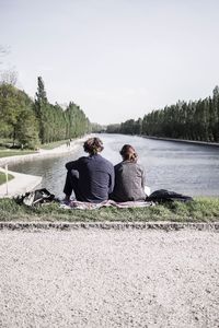 Rear view of couple sitting by river