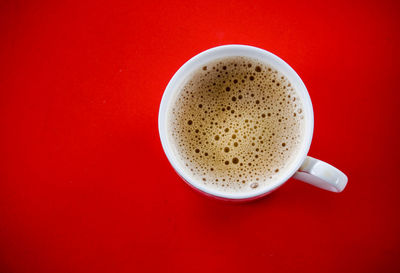 Close-up of cappuccino on table against red background