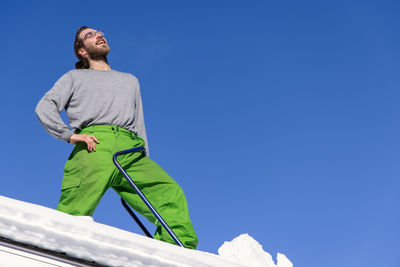 Low angle view of man standing against clear blue sky